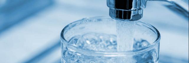 Glas unetr laufendem Wasserhahn