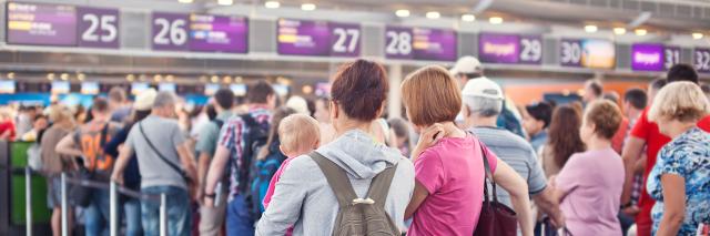 Eine Schlange von Menschen steht vor einem Schalter am Flughafen.