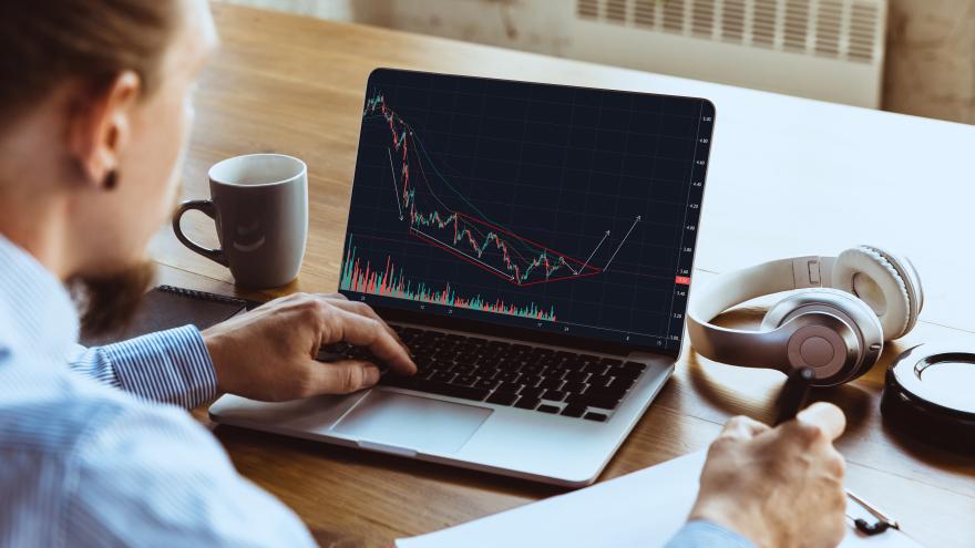 Ein Mann sitzt am Laptop und schaut sich die Aktienkurse an.